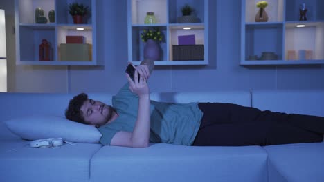 Man-lying-on-sofa-is-using-phone.-Pleasant-and-comfortable-posture.